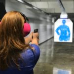 A woman practicing shooting a gun at a target